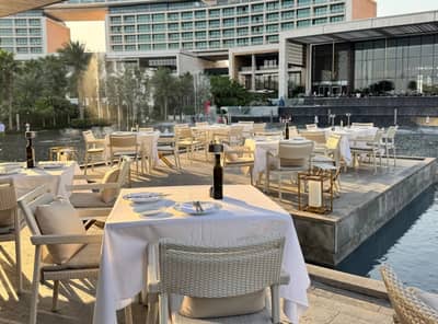 Outdoor dining area with tables and chairs at Estiatorio Milos Dubai, UAE.